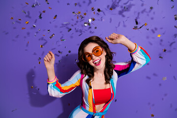 Photo of energetic active lady dancing moving on holiday with flying confetti isolated on violet color background