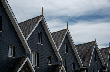 Wooden house roof attics against cloudy sky. Home residential building. Traditional british houses - obrazy, fototapety, plakaty
