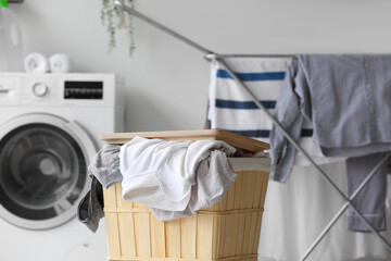 Basket with dirty clothes in laundry room, closeup