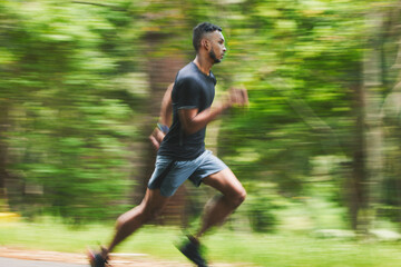 Sports man, action and running in park with speed, cardio workout or power of motion blur. Runner,...