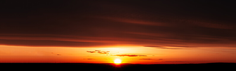 Panoramic banner view, landscape of beautiful and colourful sunset with dark clouds.