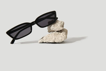 Stones with stylish sunglasses on grey background