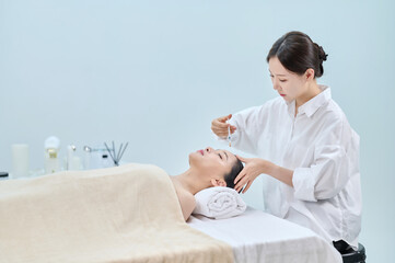 아시아 한국의 젊은 여성이 피부과 병원 또는 성형외과의 침대에 누워...