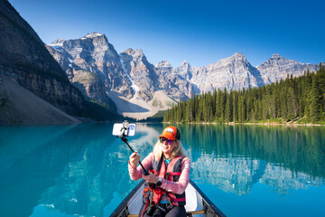 Woman taking photos, Moraine Lake during summer in .Banff National Park, Canadian Rockies, Alberta, Canada...Banff National Park, Alberta, Canada