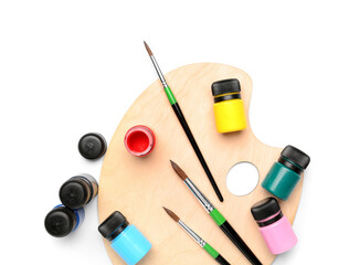 Jars of colorful gouache paints with artist's palette and brushes on white background