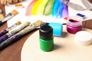 Jar of green gouache paint with artist's supplies on table