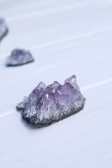 The stones of Amethyst mineral on a white wooden background, close up.