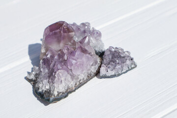 The stones of Amethyst mineral on a white wooden background, close up.