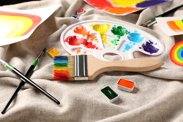 Artist's palette and brushes with paints on cloth background