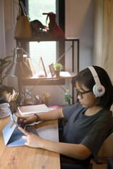 Vertical of Asian children using digital tablet with stylus pen write and do homework at home....