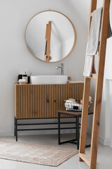 Fototapeta na wymiar Sink bowl and bath accessories on wooden cabinet in interior of light bathroom
