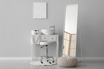 Interior of bathroom with sink bowl on dressing table, stool and mirror