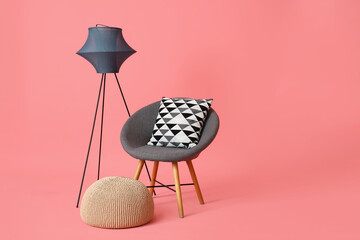 Grey armchair with pouf and lamp on pink background