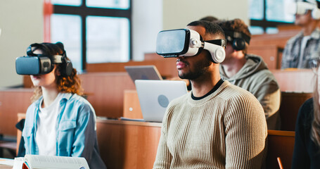 Back view of professor talking with laptop in front of mixed-races students in VR glasses. Multiethnic males and females learning high tech and listening to teacher at lection. Techonology education.