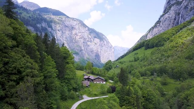 Drone shot over famous Lauterbrunnen Valley in Switzerland with stunning cliffs, huge waterfall and peaceful nature.