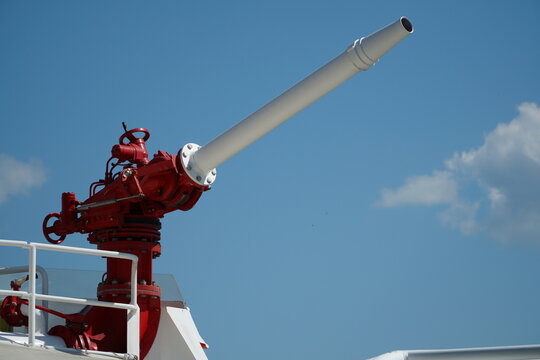 Red and white water cannon on a fireboat to extinguish a fire on the blue sky background