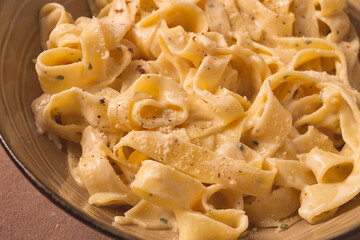 Fettuccine, tagliatelle, in creamy garlic sauce, Italian traditional cuisine, pasta carbonaro,