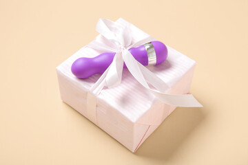 Gift box and vibrator on beige background, closeup