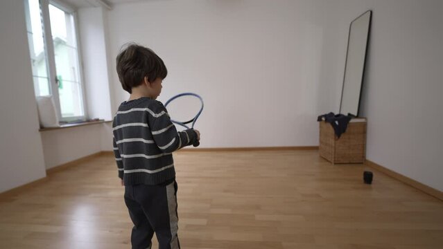 New Beginnings: Small Boy's Tennis Session in Empty Apartment Bedroom, sportive child practices at home by hitting ball with racket