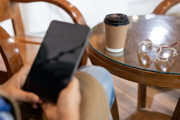 Closeup of senior female hands playing on tablet Focusing on the coffee mugs and glasses of the elderly on the table.
Use the internet to relax during the day.
drinking coffee during leisure time