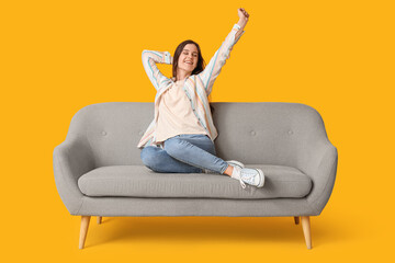 Young woman resting on sofa against yellow background