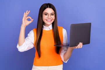 Photo of friendly young girl preteen showing okey sign good job hold new acer laptop fast speed...
