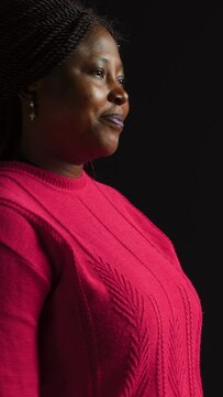 vertical video Side-view portrait of female model performing timeout, pause motion on camera. African american woman in black background displaying a t shape stop symbol with her arms, indicating no.