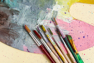 Artist's brushes and paint palette on beige background