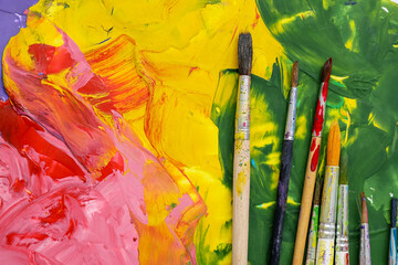 Artist's brushes on colorful painting, closeup