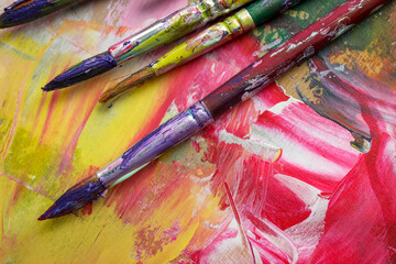 Dirty paint brushes on colorful background