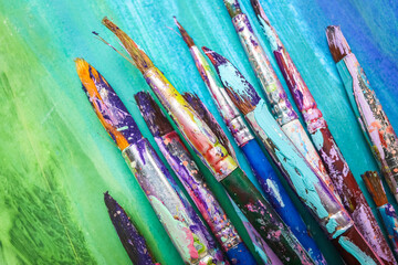 Dirty paint brushes on colorful background