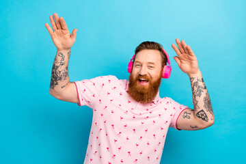 Photo of attractive positive man have good mood listen new single arms dancing isolated on blue...