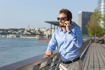 Young businessman talking on the smartphone by the riverside