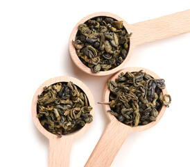 Wooden spoons with dry green tea leaves on white background