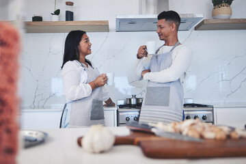 Fototapeta premium Couple in kitchen, coffee and cooking together with conversation, smile and love in home. Relax, man and woman in bonding discussion, making food for dinner vegetables and drinking tea in apartment.