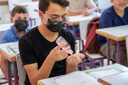 Teenager In School Sterilizing His Hands While Wearing Face Mask To Prevent Infection