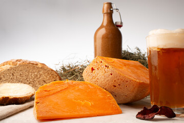 Mimolette Käse mit Brot, Butter, Bier und Gemüsechips an Heu Close up