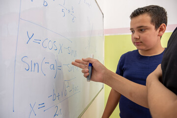 Two students are studying together using the whiteboard in school
