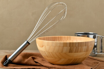 Set of baking utensils with towel on wooden table near brown wall