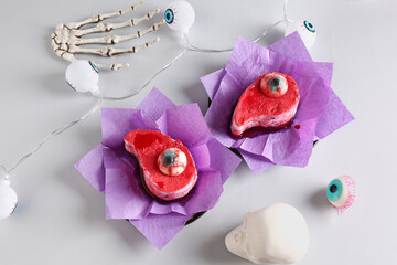 Delicious fruit cakes, skeleton hand and skull for Halloween celebration on white background