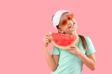 Happy little girl in sunglasses with slice of fresh watermelon on pink background