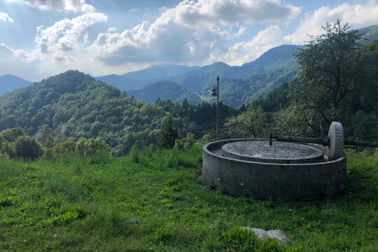 Ancient Millstone with a Beautiful View on the Julian Alps in a Cloudy Summer Day. Clabuzzaro, Drenchia, Udine Province, Italy