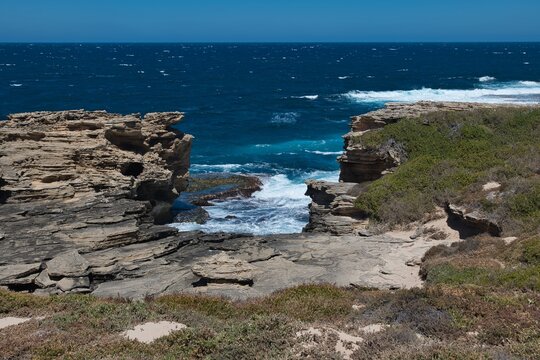 Wild and rocky cliffs of Rottnest Islands, Western Australia. Dark blue sea and cliffs. Beautiful landscape of Rottnest Island. Famous western Australian holiday destination.  