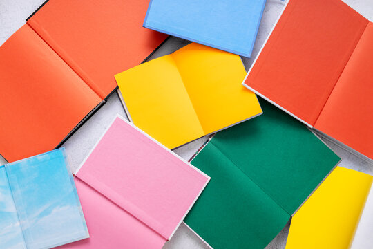 Top view of colorful endpapers on the white table. Opened books with empty firts pages