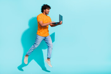 Full body profile photo of excited person jumping hold use netbook eshopping empty space isolated on teal color background