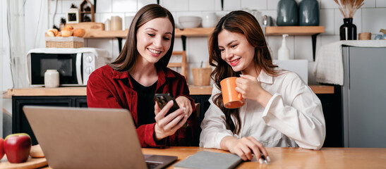 Two young woman using smartphone to search business information and reading data together to brainstorming