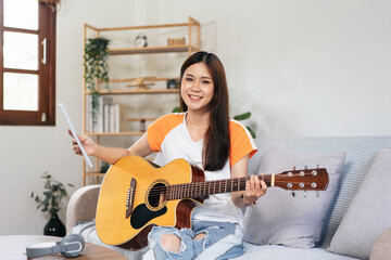 Young woman is holding a book of lyrics and chords to playing guitar and practice to singing the...