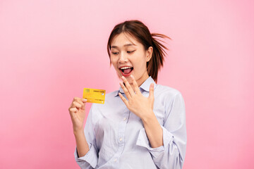 Young asian woman holding credit card and raising one hand to covering mouth while feeling surprised