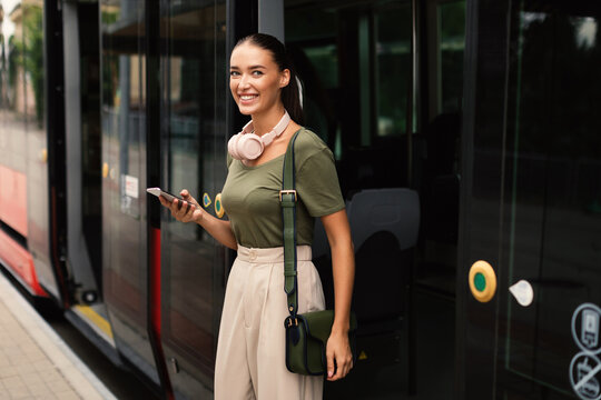 Joyful Passenger Young Lady Exiting Tram, Texting on Phone