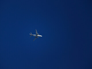 jet plane with white fuselage crossing a cloudless blue sky.